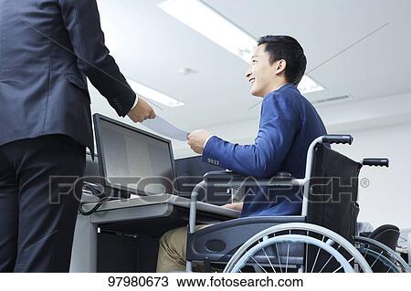 Stock Image - Japanese young man on wheelchair working. Fotosearch