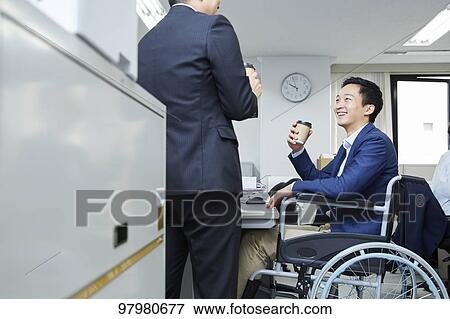 Stock Photo - Japanese young man on wheelchair working. Fotosearch