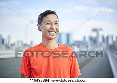 Picture - Mature Japanese man running downtown Osaka, Japan. Fotosearch