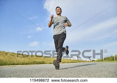 Stock Image - Mature Japanese man running downtown Osaka, Japan. Fotosearch