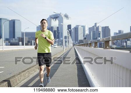 Stock Image - Mature Japanese man running downtown Osaka, Japan. Fotosearch