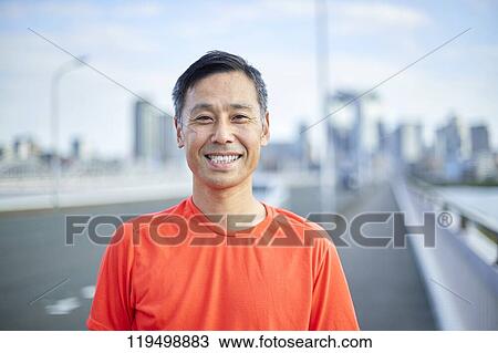 Stock Image - Mature Japanese man running downtown Osaka, Japan. Fotosearch