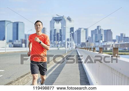 Stock Photo - Mature Japanese man running downtown Osaka, Japan. Fotosearch
