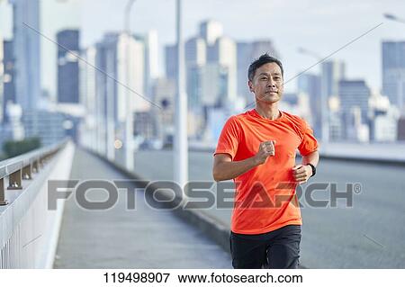 Stock Photo - Mature Japanese man running downtown Osaka, Japan. Fotosearch