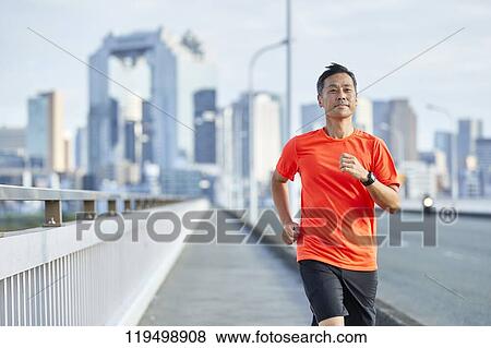 Stock Photo - Mature Japanese man running downtown Osaka, Japan. Fotosearch