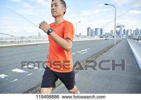 Stock Photograph - Mature Japanese man running downtown Osaka, Japan. Fotosearch