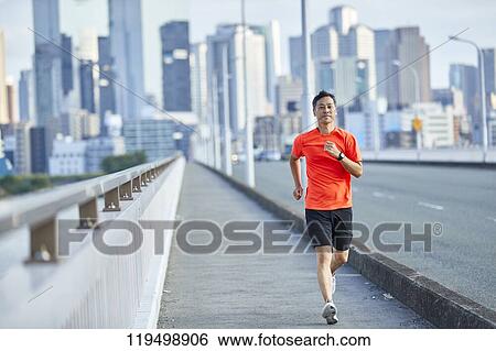 Stock Photograph - Mature Japanese man running downtown Osaka, Japan. Fotosearch