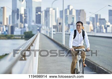 Picture - Mature Japanese man with bike downtown Osaka, Japan. Fotosearch