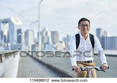 Stock Image - Mature Japanese man with bike downtown Osaka, Japan. Fotosearch