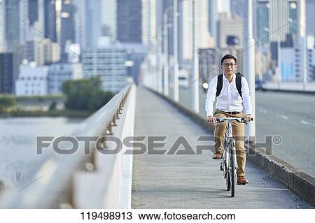 Stock Image - Mature Japanese man with bike downtown Osaka, Japan. Fotosearch