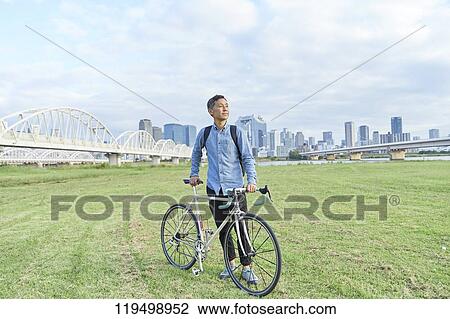 Stock Image - Mature Japanese man with bike downtown Osaka, Japan. Fotosearch