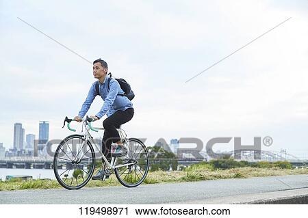 Stock Image - Mature Japanese man with bike downtown Osaka, Japan. Fotosearch