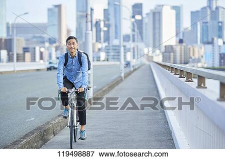 Stock Photo - Mature Japanese man with bike downtown Osaka, Japan. Fotosearch