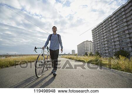 Stock Photo - Mature Japanese man with bike downtown Osaka, Japan. Fotosearch