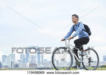Stock Photo - Mature Japanese man with bike downtown Osaka, Japan. Fotosearch