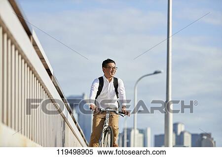 Stock Photography - Mature Japanese man with bike downtown Osaka, Japan. Fotosearch