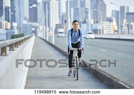 Stock Photography - Mature Japanese man with bike downtown Osaka, Japan. Fotosearch