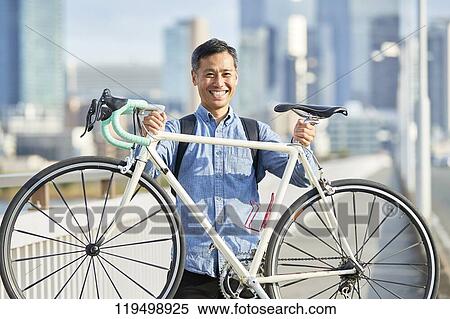 Stock Photography - Mature Japanese man with bike downtown Osaka, Japan. Fotosearch