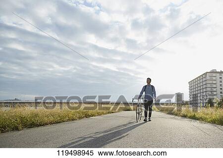 Stock Photography - Mature Japanese man with bike downtown Osaka, Japan. Fotosearch