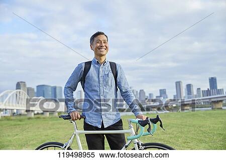 Stock Photography - Mature Japanese man with bike downtown Osaka, Japan. Fotosearch