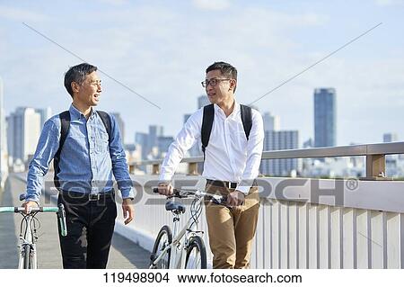 Picture - Mature Japanese men with bikes downtown Osaka, Japan. Fotosearch