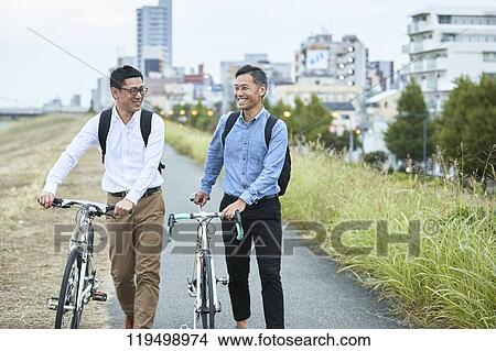 Picture - Mature Japanese men with bikes downtown Osaka, Japan. Fotosearch