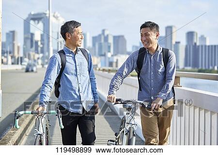 Stock Photo - Mature Japanese men with bikes downtown Osaka, Japan. Fotosearch