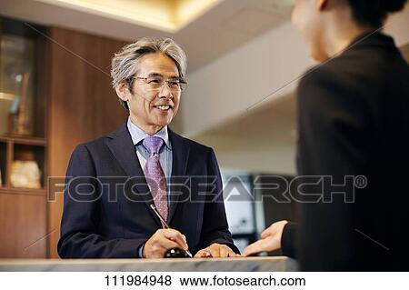 Stock Photo - Senior businessman checking in at hotel. Fotosearch