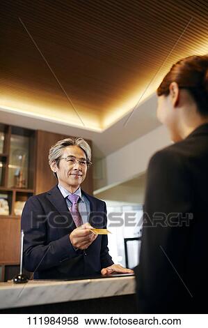 Stock Photo - Senior businessman checking in at hotel. Fotosearch