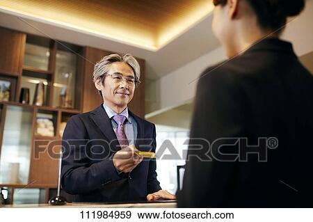 Stock Photo - Senior businessman checking in at hotel. Fotosearch