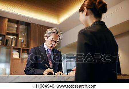 Stock Photograph - Senior businessman checking in at hotel. Fotosearch