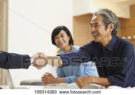 Stock Image - Senior Japanese couple at home with salesman. Fotosearch