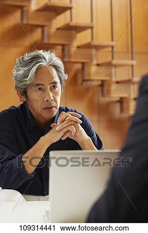 Stock Image - Senior Japanese couple at home with salesman. Fotosearch