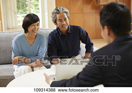 Stock Photo - Senior Japanese couple at home with salesman. Fotosearch
