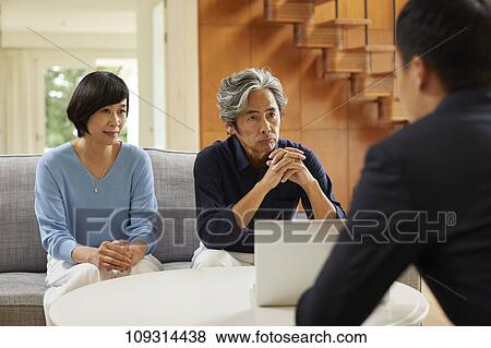 Stock Photo - Senior Japanese couple at home with salesman. Fotosearch