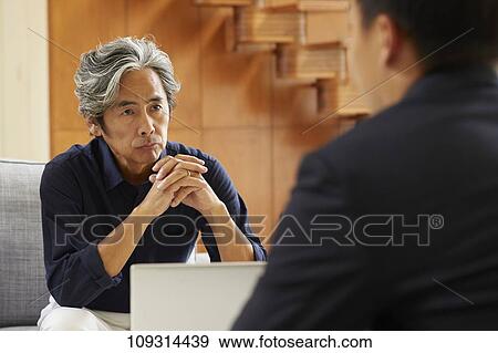 Stock Photo - Senior Japanese couple at home with salesman. Fotosearch