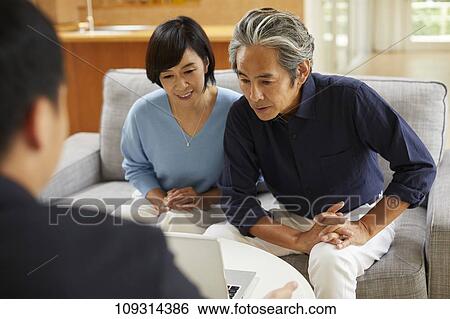 Stock Photograph - Senior Japanese couple at home with salesman. Fotosearch
