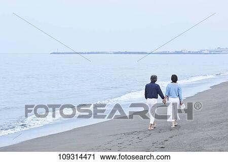 Stock Image - Senior Japanese couple at the beach. Fotosearch