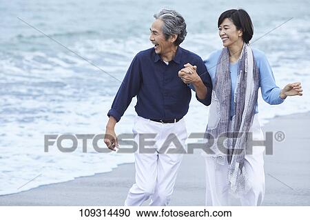 Stock Image - Senior Japanese couple at the beach. Fotosearch