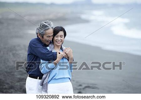 Stock Image - Senior Japanese couple at the beach. Fotosearch