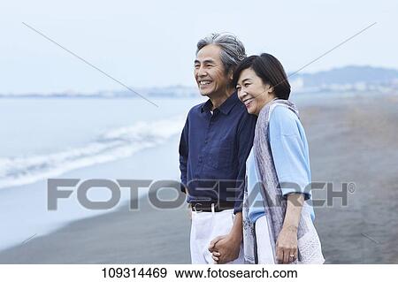 Stock Photo - Senior Japanese couple at the beach. Fotosearch