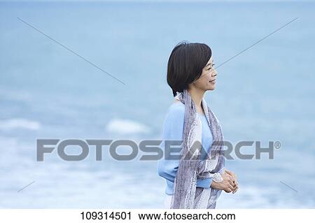 Stock Image - Senior Japanese woman at the beach. Fotosearch