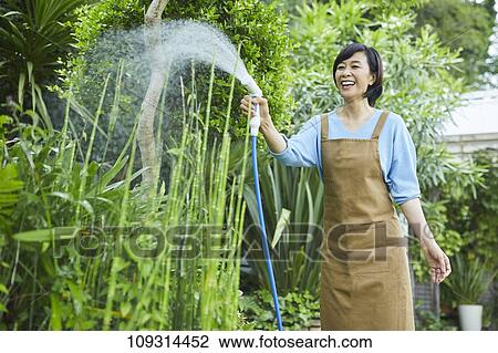 Stock Image - Senior Japanese woman gardening. Fotosearch