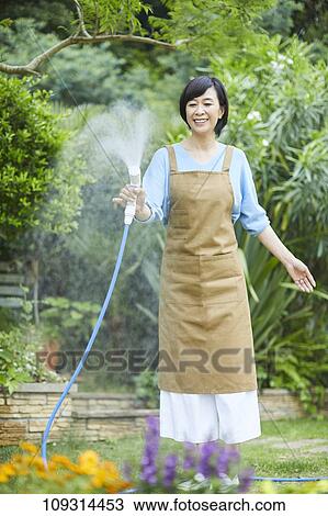 Stock Image - Senior Japanese woman gardening. Fotosearch