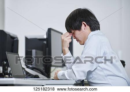 Tired Japanese businessman in the office View Large Photo Image Stock Photo - Tired Japanese businessman in the office. Fotosearch