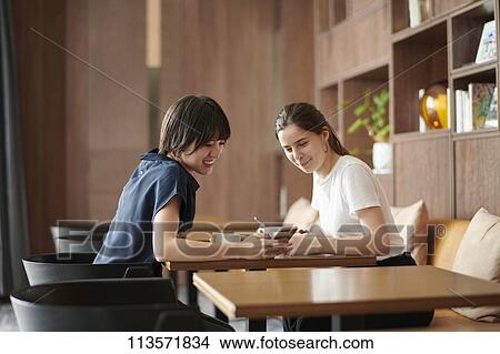 Picture - Young girlfriends at a cafe. Fotosearch