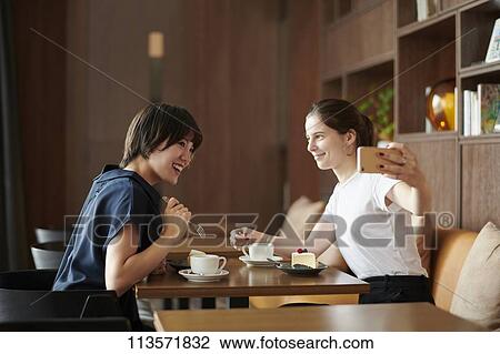 Young girlfriends at a cafe View Large Photo Image Stock Image - Young girlfriends at a cafe. Fotosearch