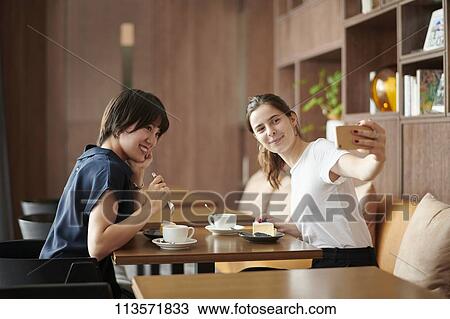 Young girlfriends at a cafe View Large Photo Image Stock Image - Young girlfriends at a cafe. Fotosearch