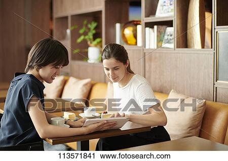 Young girlfriends at a cafe View Large Photo Image Stock Image - Young girlfriends at a cafe. Fotosearch