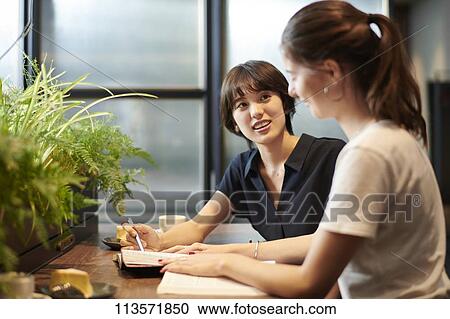 Stock Image - Young girlfriends at a cafe. Fotosearch